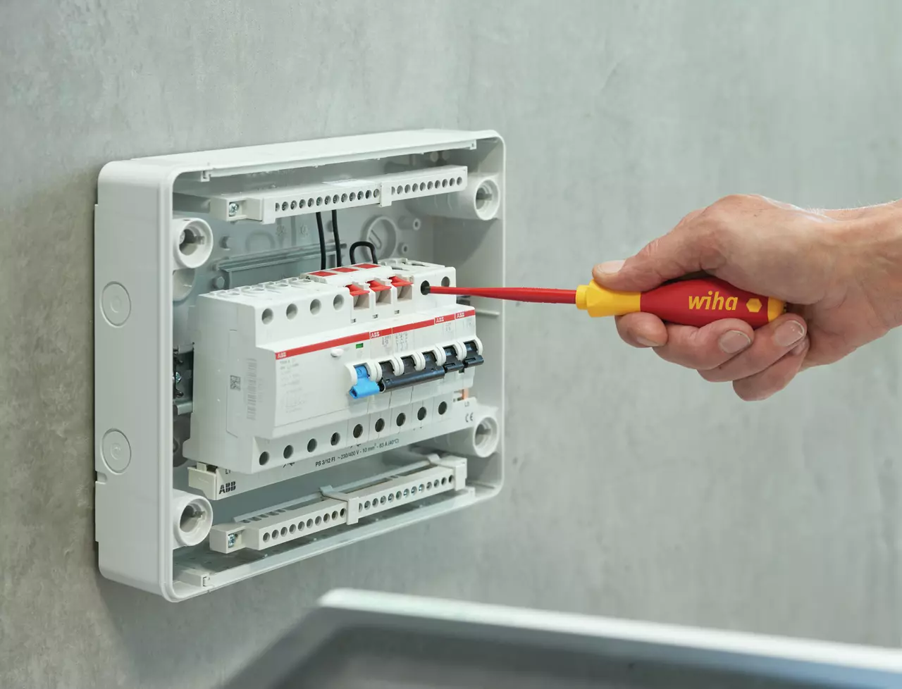 Vissage sur un disjoncteur modulaire dans un coffret électrique mural avec un tournevis isolé Wiha SoftFinish electric slimFix du jeu 35389